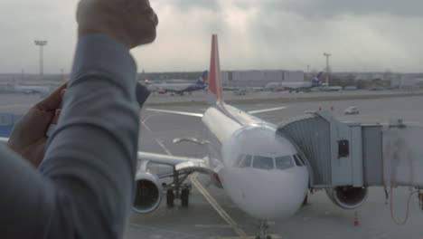 Close-up-view-of-woman-using-mobile-terminal-on-smartphone-to-make-online-payment-by-credit-card-near-airport-window