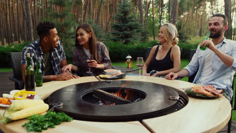 amigos alegres relajándose cerca de la parrilla de barbacoa