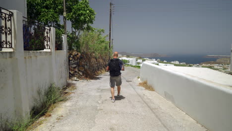 siguiendo a un hombre caminando por una calle estrecha de una isla griega-1