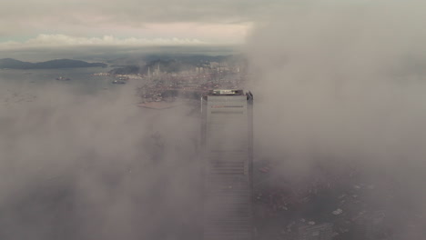 rascacielos icc que aparece entre nubes bajas en hong kong