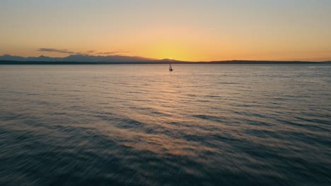 disparo aéreo de aproximación de un barco de vela en el mar contra el atardecer dorado por la noche