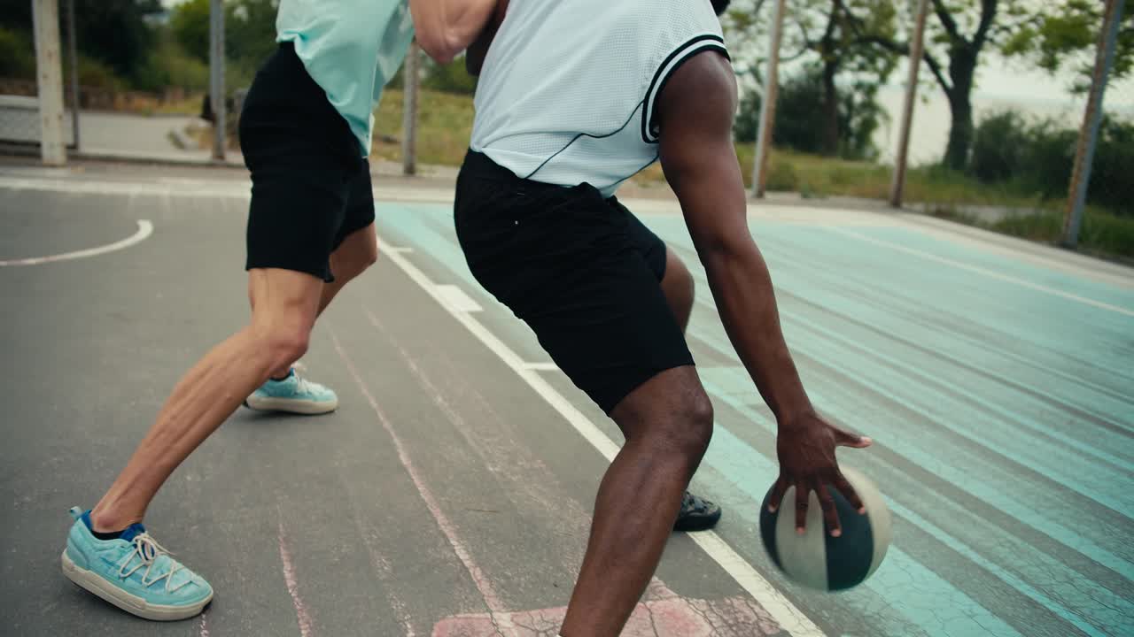 Close-up shot of a Black man in a white t-shirt bypassing his opponent in a light green t-shirt and scoring a brilliant goal into the basketball goal on the outside basketball card