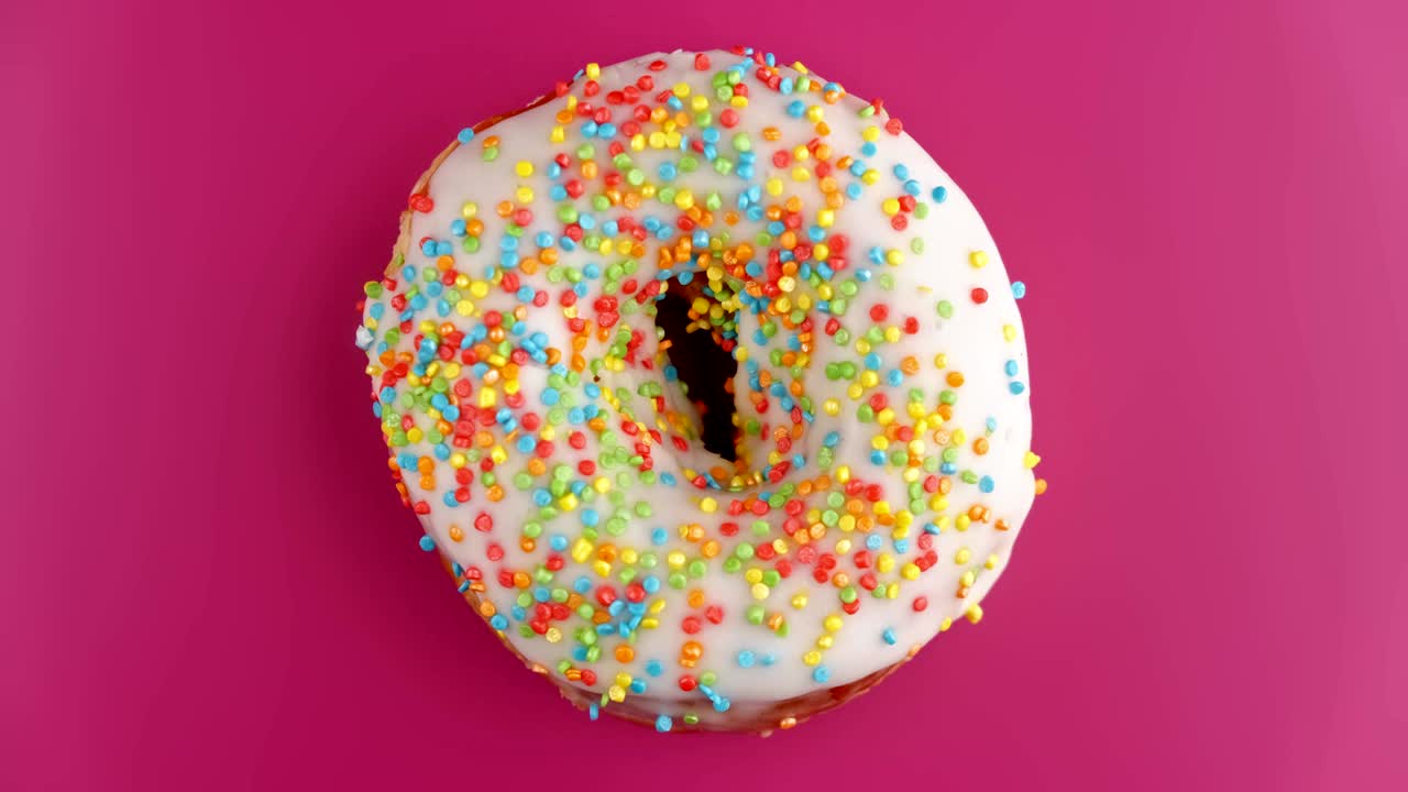вкусный сладкий пончик вращается на розовом фоне. верхний вид красочного пончика