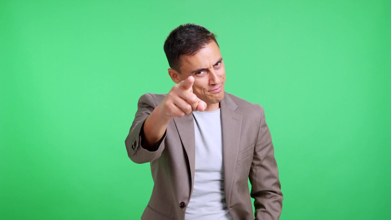 Confident man pointing finger at camera on green screen