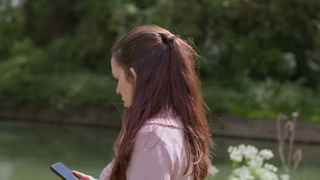 Stressed-And-Worried-Woman-Outdoors-With-Financial-Worries-About-Cost-Of-Living-Crisis-Debt-And-Paying-Bills-Looking-At-Mobile-Phone-By-Riverbank-1