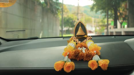 Buddhist-Ornament-with-Yellow-Traditional-Flowers-on-the-Dashboard-of-a-Car-Traveling-in-Thailand
