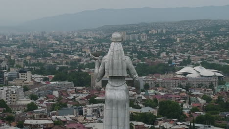 toma aérea de arco de la estatua de kartlis deda con el paisaje urbano de tbilisi en la parte posterior