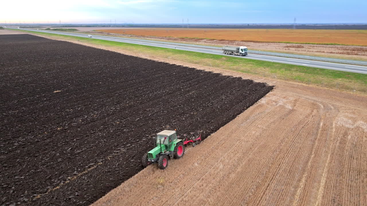 Tractor plowing field near highway