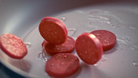 sliced turkish sausages (sucuk) fall into the pan in slow motion.