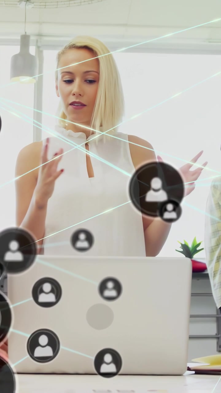 Video verticale: Donna che conduce una riunione tecnologica con un laptop, parla mentre icone UI si sovrappongono al telefono.