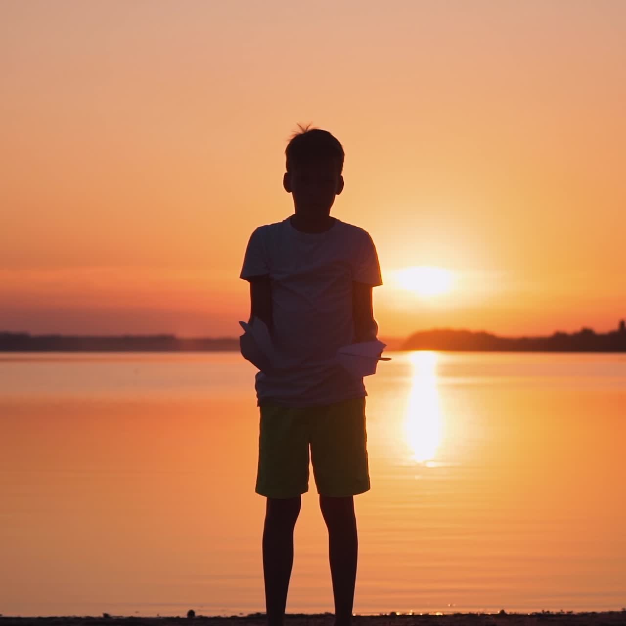 Little boy with paper plane. Beautiful sunset. Origami.