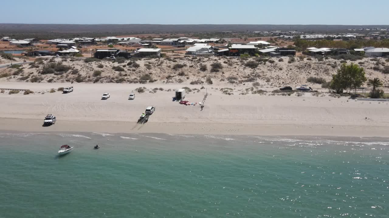 4 k lateral volando sobre la costa con tracción en las 4 ruedas, barcos, personas en vacaciones con agua verde del océano