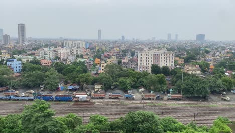 Vista-Aérea-De-Un-Tren-En-Movimiento-Y-Múltiples-Vías-Con-Una-Hermosa-Vista-De-La-Ciudad