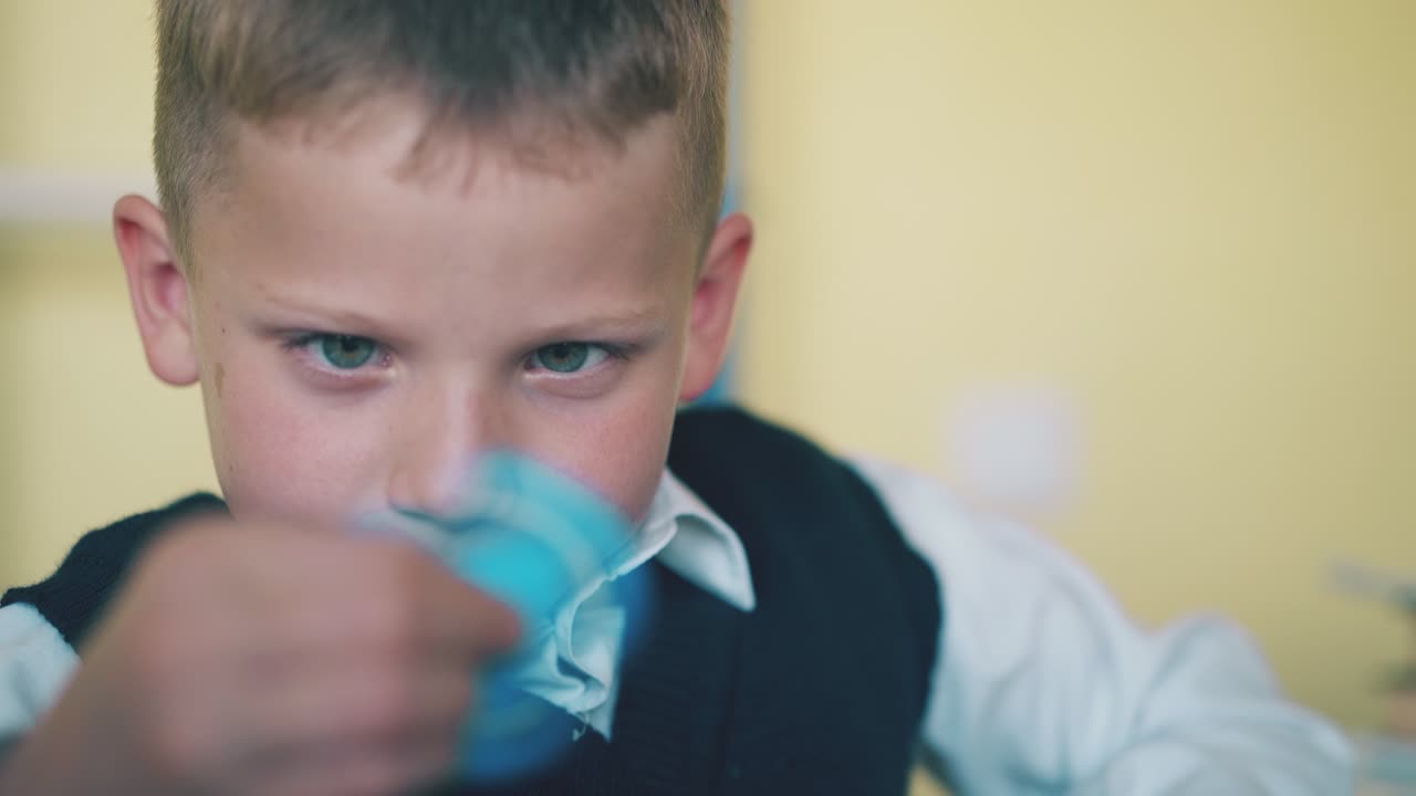 행복한 소년은 교실에서 재미있는 파란 스피너와 놀고 앉아 있습니다.