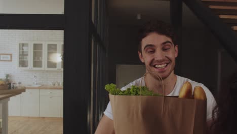 una pareja feliz trayendo comida saludable en paquetes juntos.