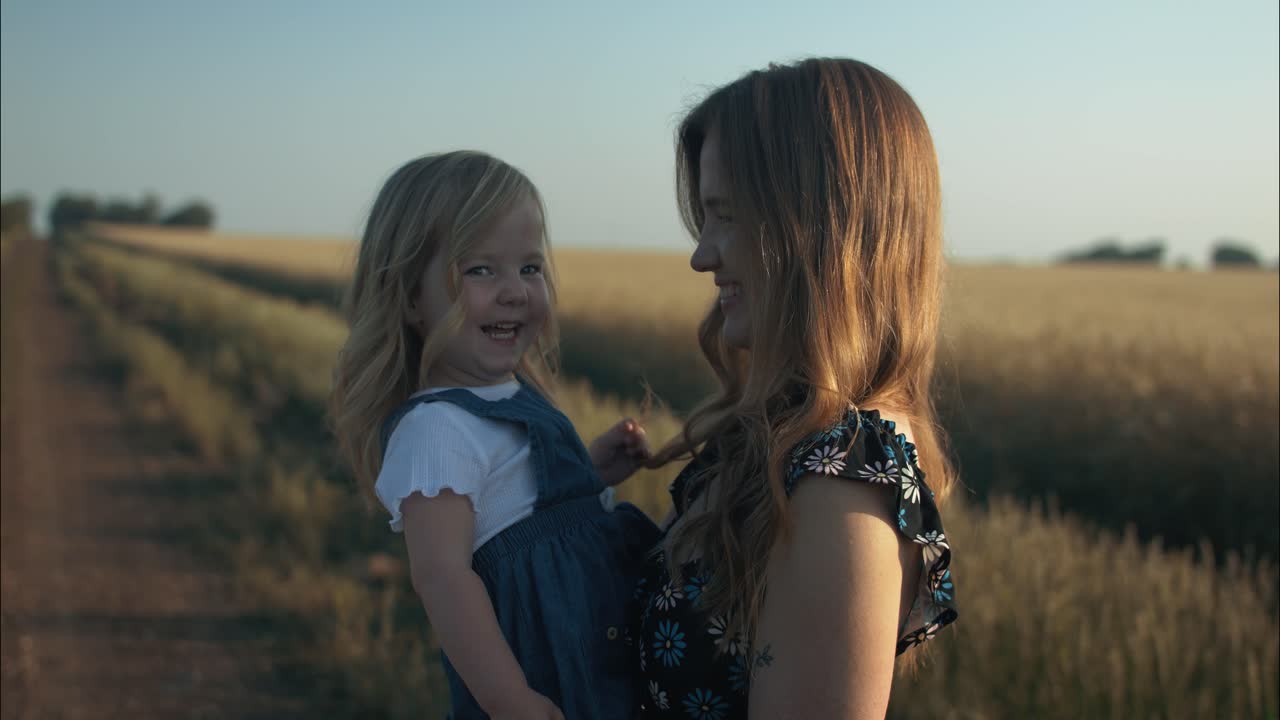 feliz, sonriente madre e hija juntos afuera en el atardecer de verano teniendo positiva, amorosa familia o el momento del día de la madre en cámara lenta cinematográfica