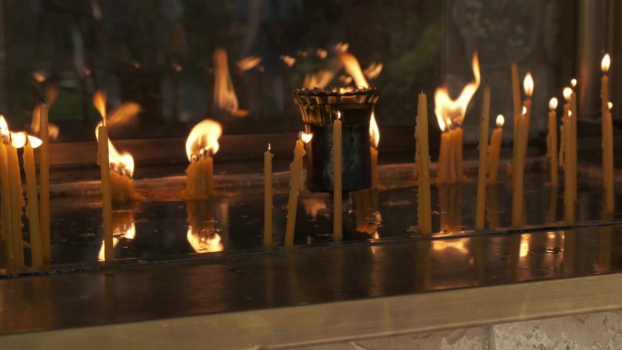Candele che bruciano al rallentatore su un centrotavola in un contesto religioso.