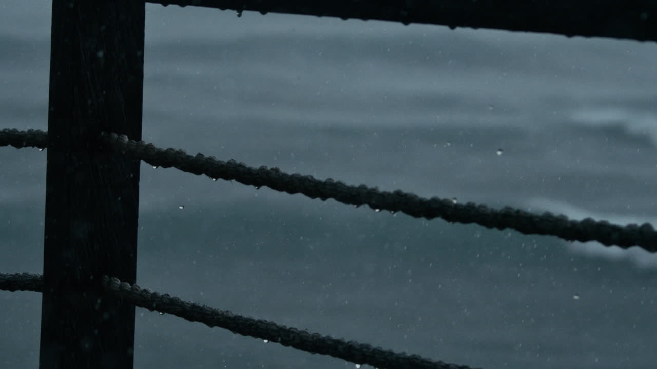 Rain gathers on rope and glistens before falling in slow motion