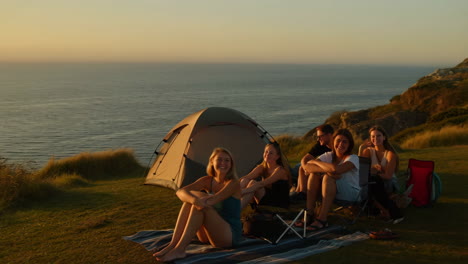 friends enjoying sunset camping by the ocean