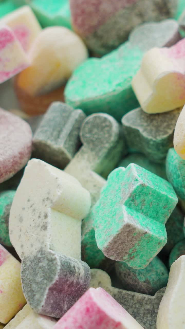 Man picks up a single candy from a large candy pile. Close up