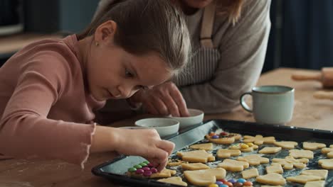 caucasian girl decorating homemade cookies with grandmother.