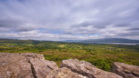 time lapse of rural landscape with rocky foreground and hills and lake in the distance on a sunny cloudy day in arigna mountains in county leitrim in ireland