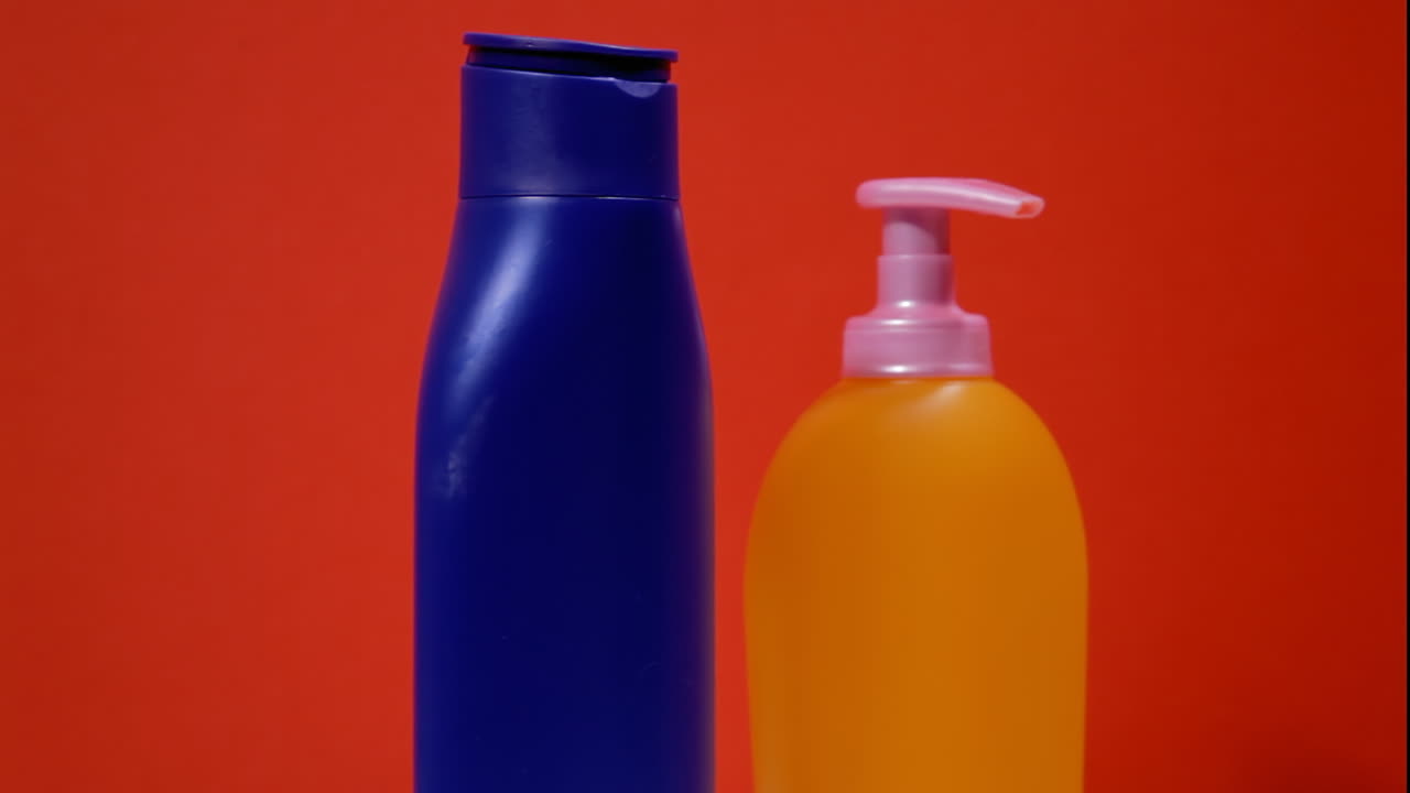 dos botellas de plástico dispensador de jabón, naranja y azul, en una superficie giratoria
