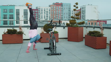 Una-Chica-Atlética-Hace-Un-Truco-Acrobático-En-Bicicleta-Haciendo-Ejercicio-En-Una-Máquina-De-Ciclismo-Estacionaria-Al-Aire-Libre