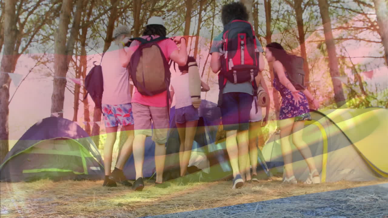 Standing with backpacks, friends in forest near tents, discussing animation project