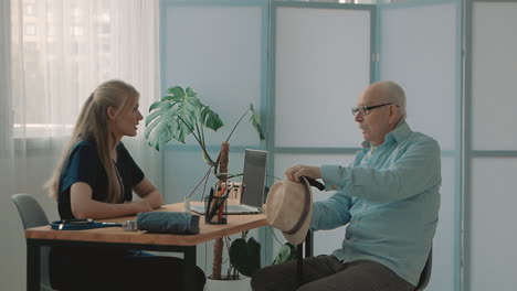 joven enfermera cariñosa hablando con un anciano en la oficina