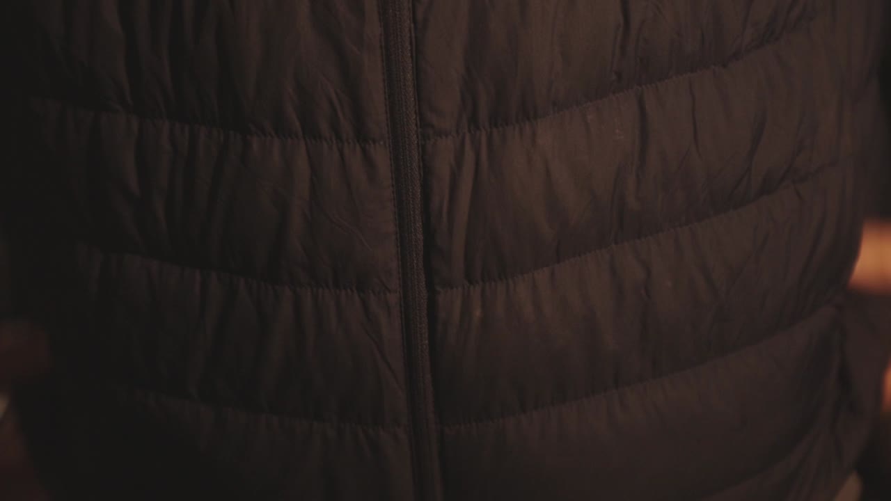 la mano de la persona abrocha la cremallera en una chaqueta negra, preparándose para caminar