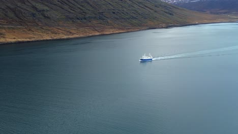 Fishing-boat-sailing-on-a-lake-next-to-some-mountains-in-Iceland