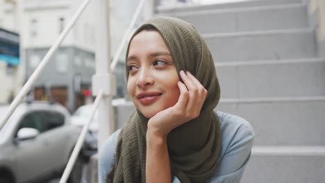 woman wearing hijab sitting on stairs in the street