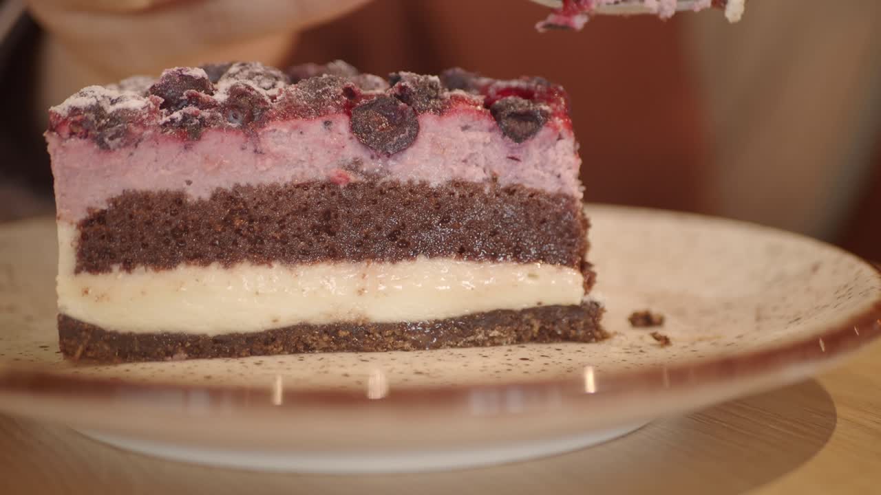 Woman eating a slice of layered chocolate cake with berries