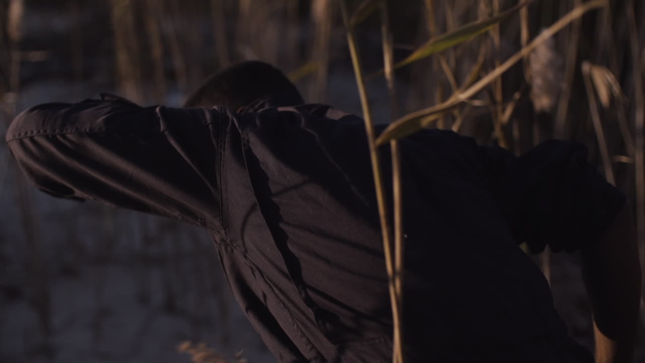 Male dancer emerges from reeds, close up, slow motion