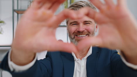 a man smiling and making a heart shape with his hands