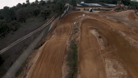 FPV-Übersicht-Entlang-Der-Motocross-Feldstrecke,-Während-Der-Fahrer-Einen-Großen-Sprung-Betritt