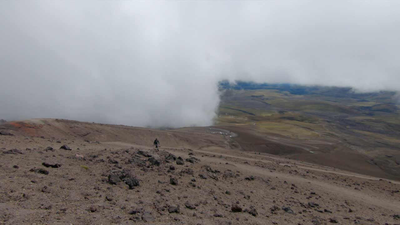 Mist and clouds surround slopes of Cotopaxi volcano, Ecuador, as solo hiker treks upward