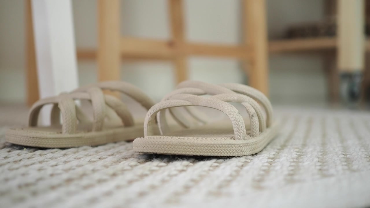Paar beige geweven sandalen op een getextureerd vloerkleed