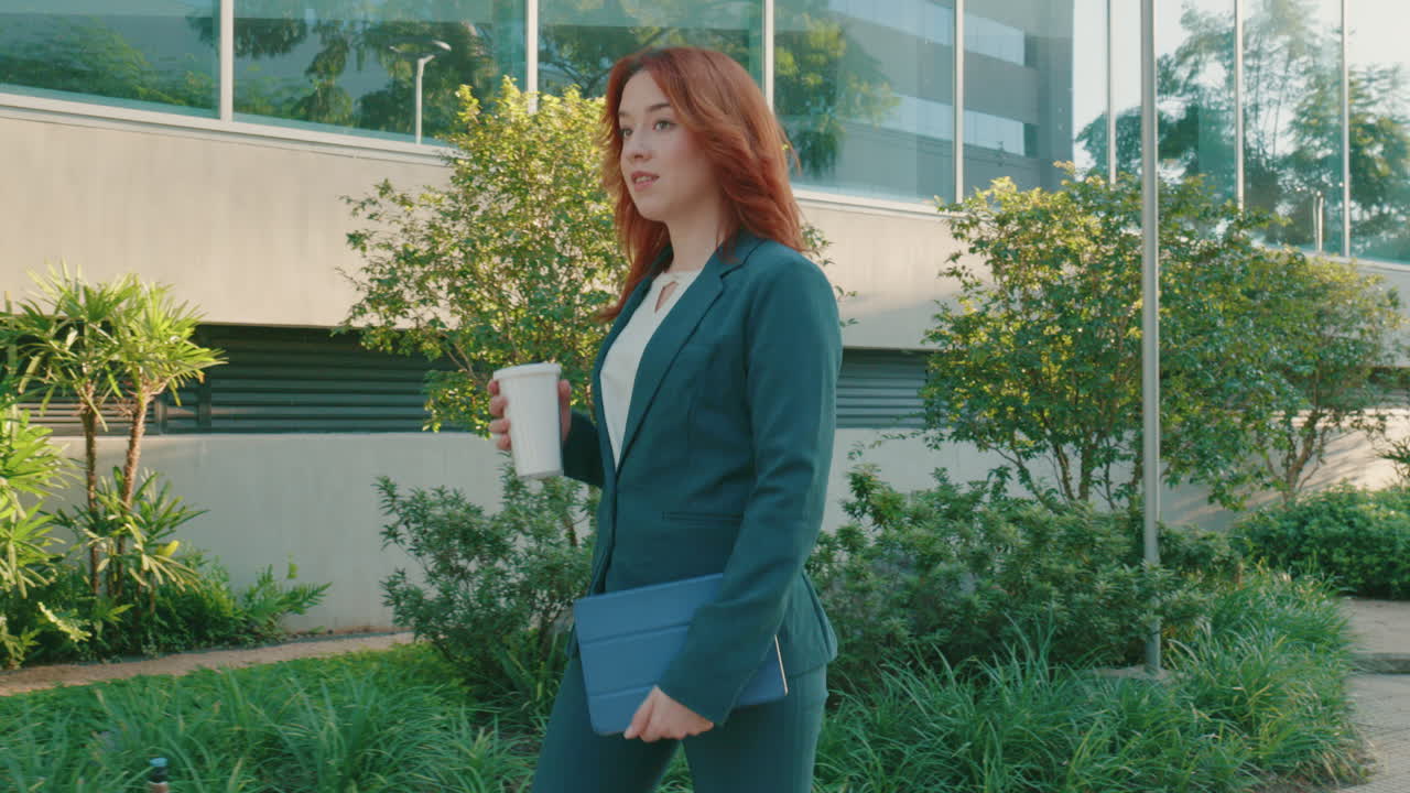 Shot of a businesswoman wearing formal suit going to office holding her tablet for work and holding a cup for coffee or tea at daytime