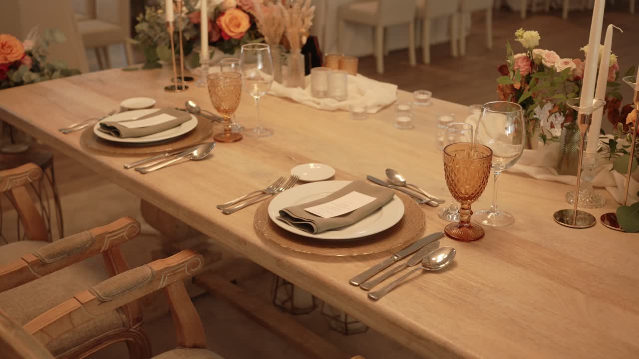 elegantly set wedding table with amber glasses and floral centerpiece under soft warm lighting