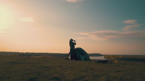 man silhouette comes to bonfire from tent in camp at sunrise