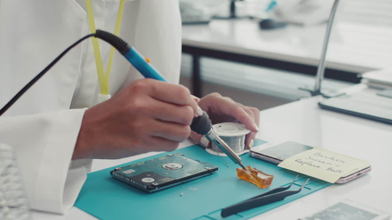 Female Technician Using Soldering Iron Repairing Hard Drive