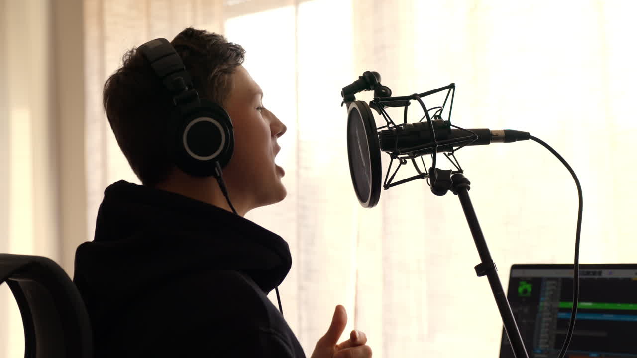 Side Profile of Male Singer Recording Vocals into Large Studio Microphone