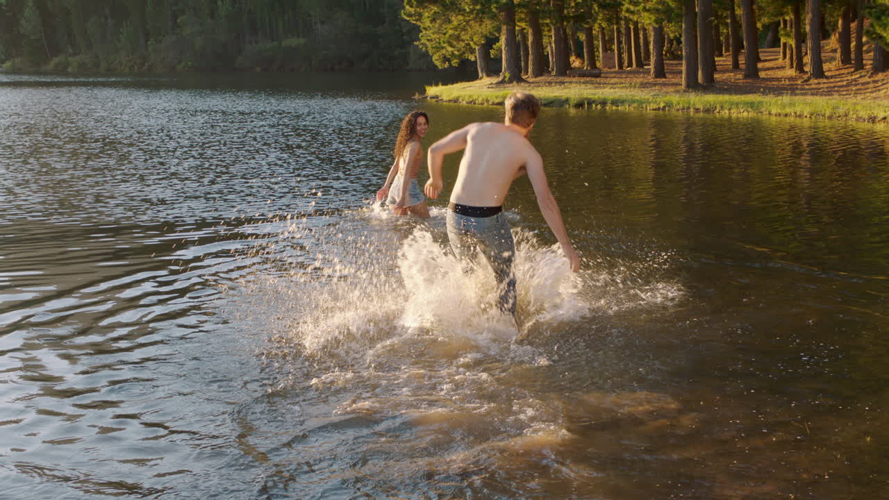 pareja feliz chapoteando en el lago al atardecer un joven recoge a su novia chapoteando en el agua divirtiéndose jugando disfrutando del romántico amor de verano