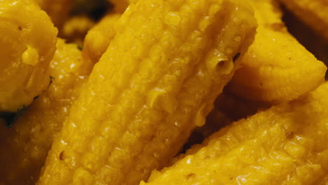 close-up of fermented yellow mini corn with black pepper on plate. preservation of vegetables in glass jars. fermentation preserved mini corns with spices macro.
