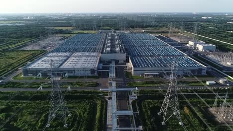 aerial view of a large industrial facility surrounded by power lines and greenery, showcasing modern architecture and extensive infrastructure in a rural setting