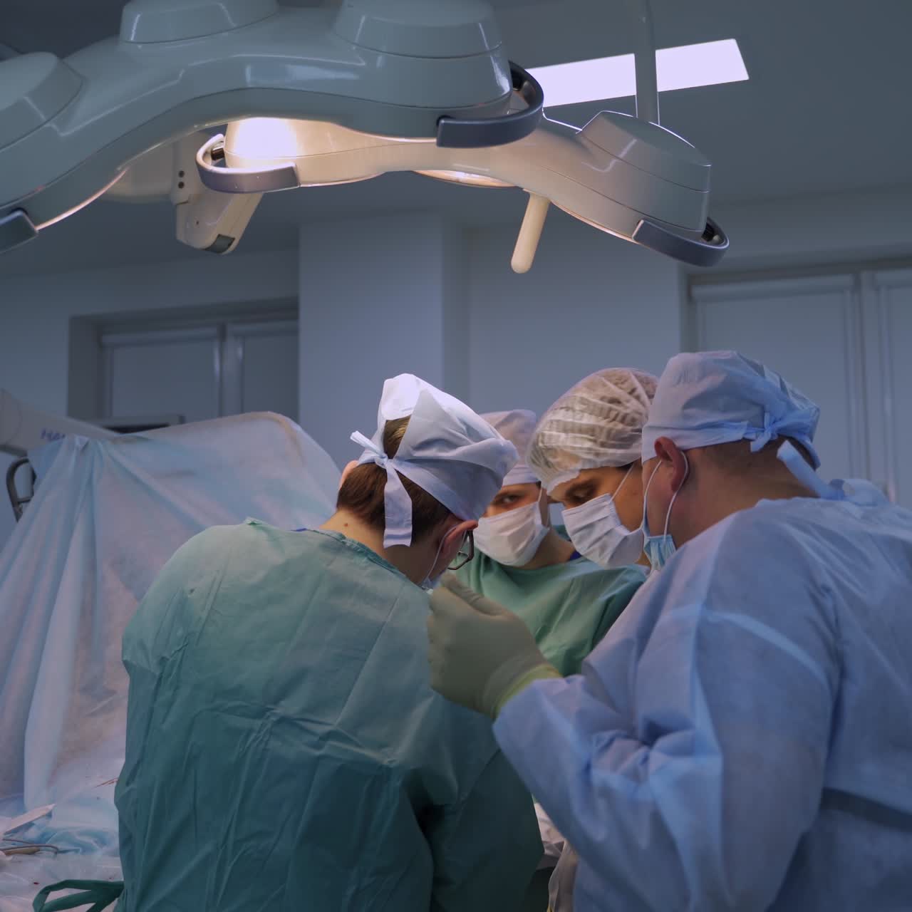 Four surgeons dealing with one patient at operation. Female nurse passing the instruments and cleaning tools
