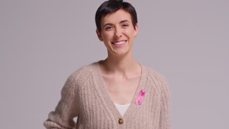 studio portrait of smiling young woman wearing pink breast cancer awareness ribbon against white background 1