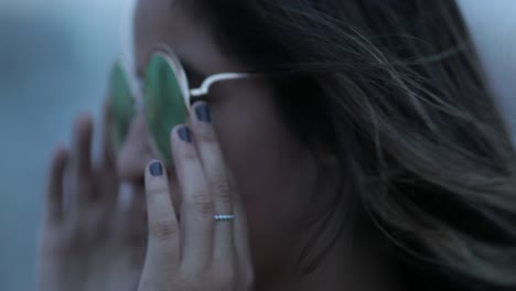 girl putting on big round sunglasses at night
